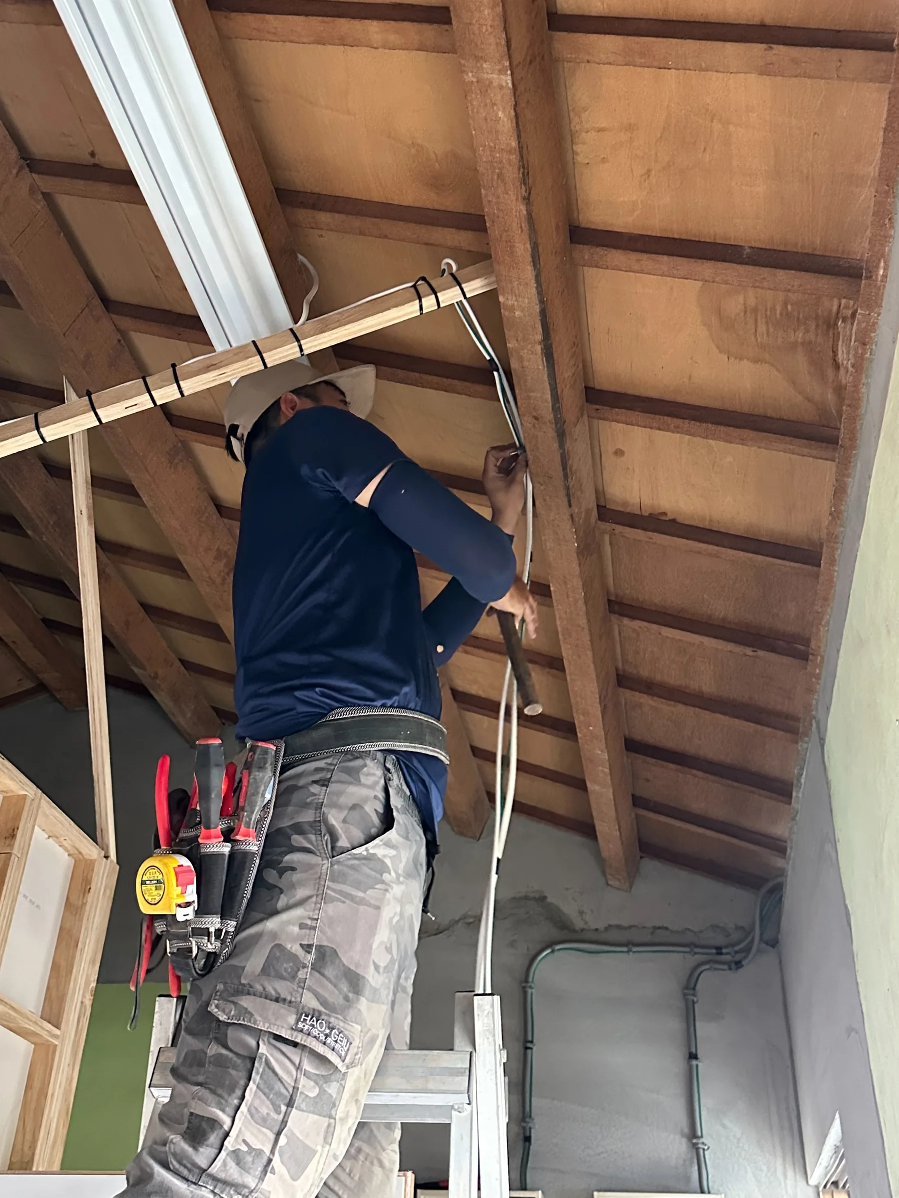 施工人員於木構屋架下進行線路施作